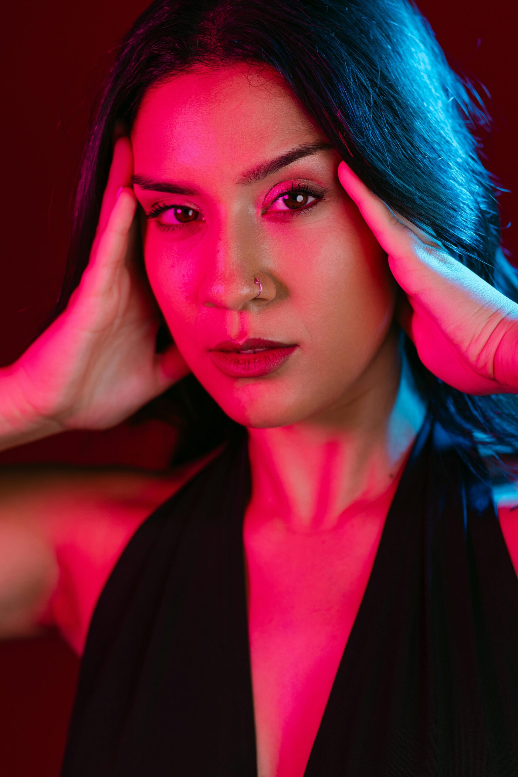 A striking portrait of a young woman illuminated with colorful lighting, showcasing elegance and emotion.
